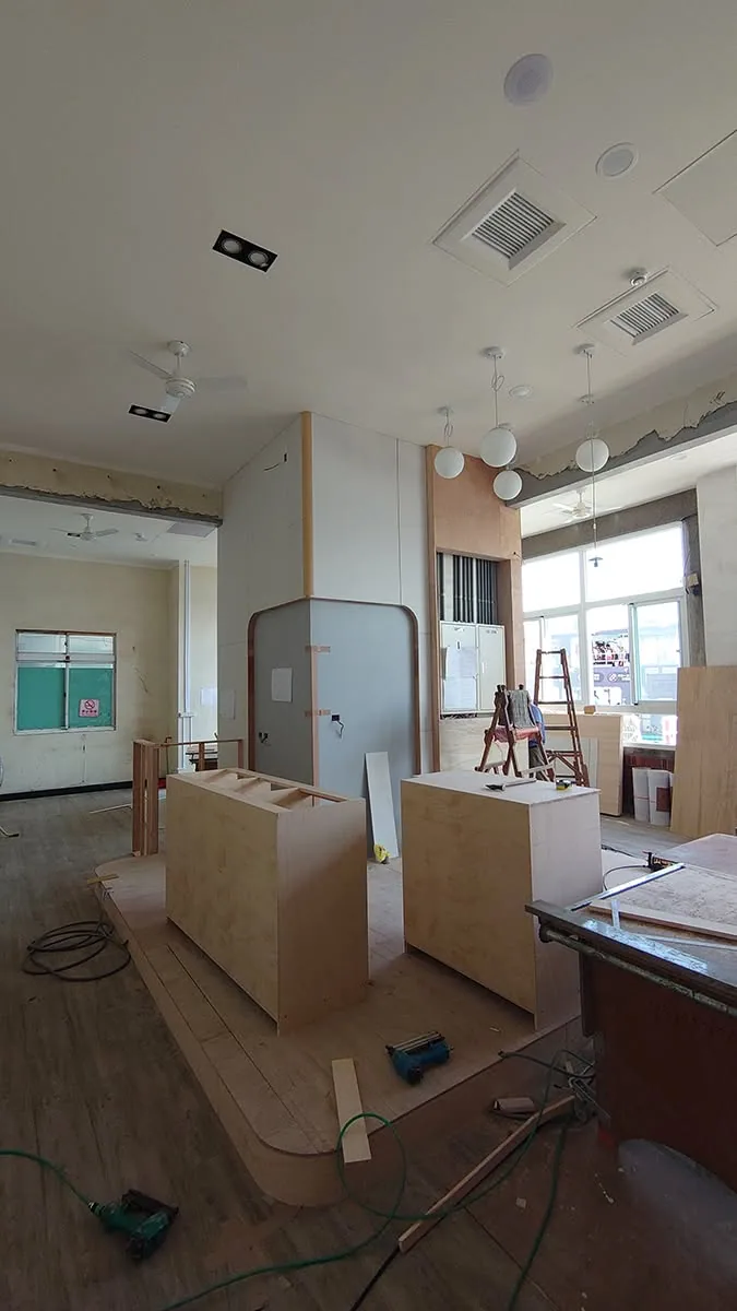 商業空間施工中,兩座板材櫃體已現場組立,天花裝設吊燈與空調出風口