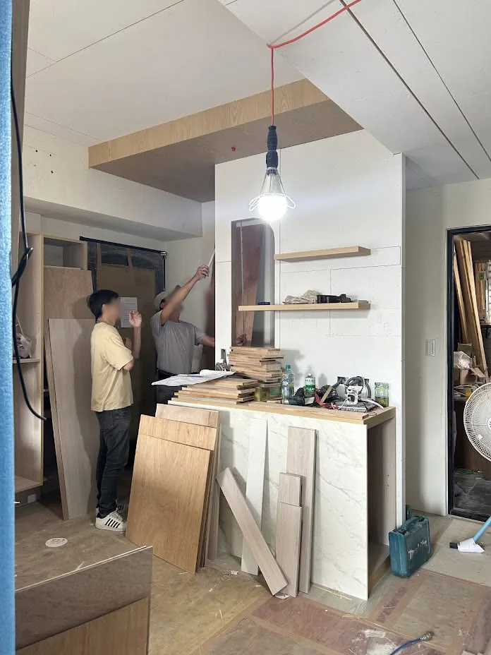 施工現場木作師傅正在進行系統櫃體組裝作業，地面鋪有保護材
