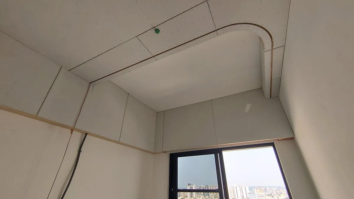 臥室天花板封板完成呈弧形轉角,預留窗簾盒與嵌燈孔位,電線外露