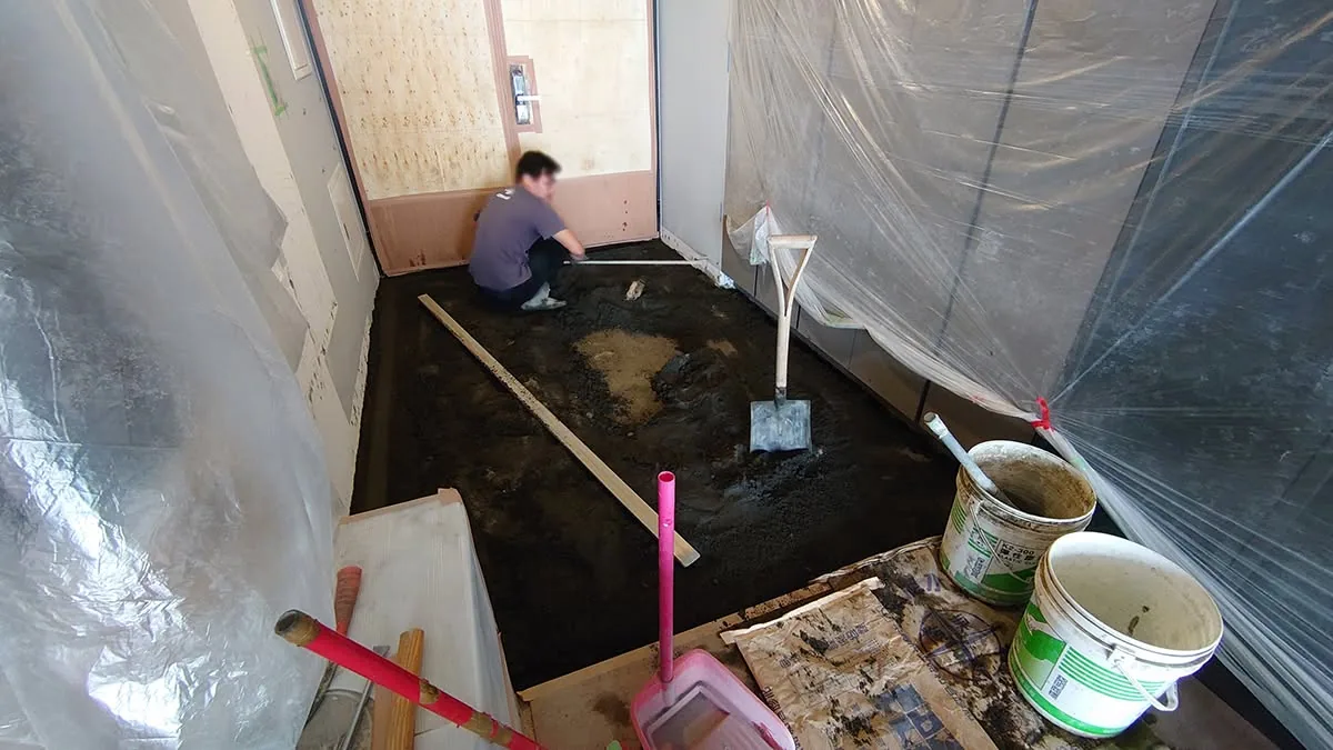 住宅翻新工程泥作施工現場，工班在地面進行水泥打底作業