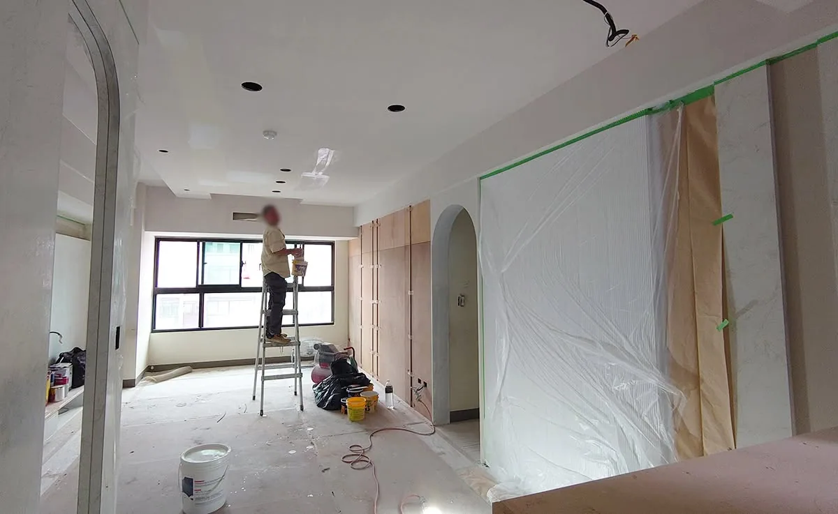 手持工具進行塗裝作業的畫面,牆面上可見新舊塗層的交界