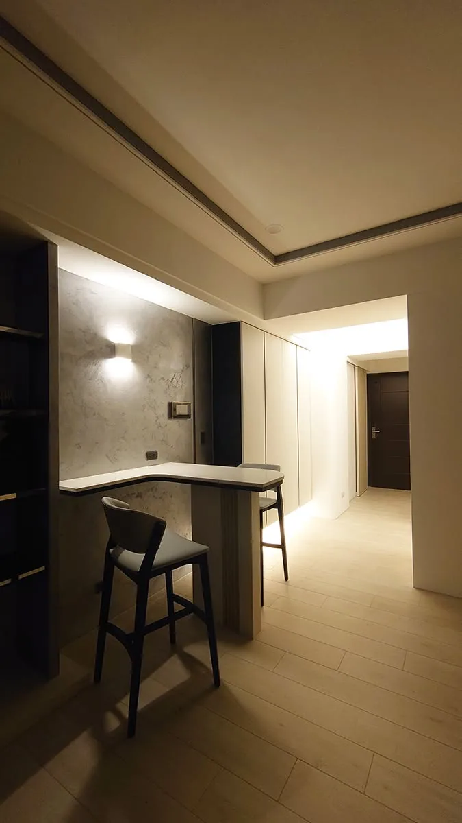 餐廳角落設置矮櫃與展示層架，搭配木質餐桌椅與柔和間接照明